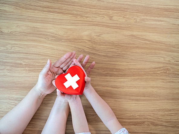 Red Cross in heart shape being held by mother and child